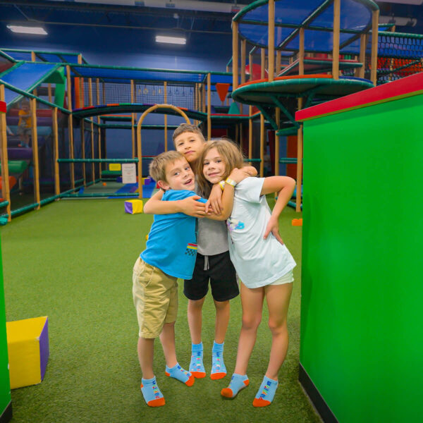 3 kids hugging at indoor playground in Mansfield Texas 76063