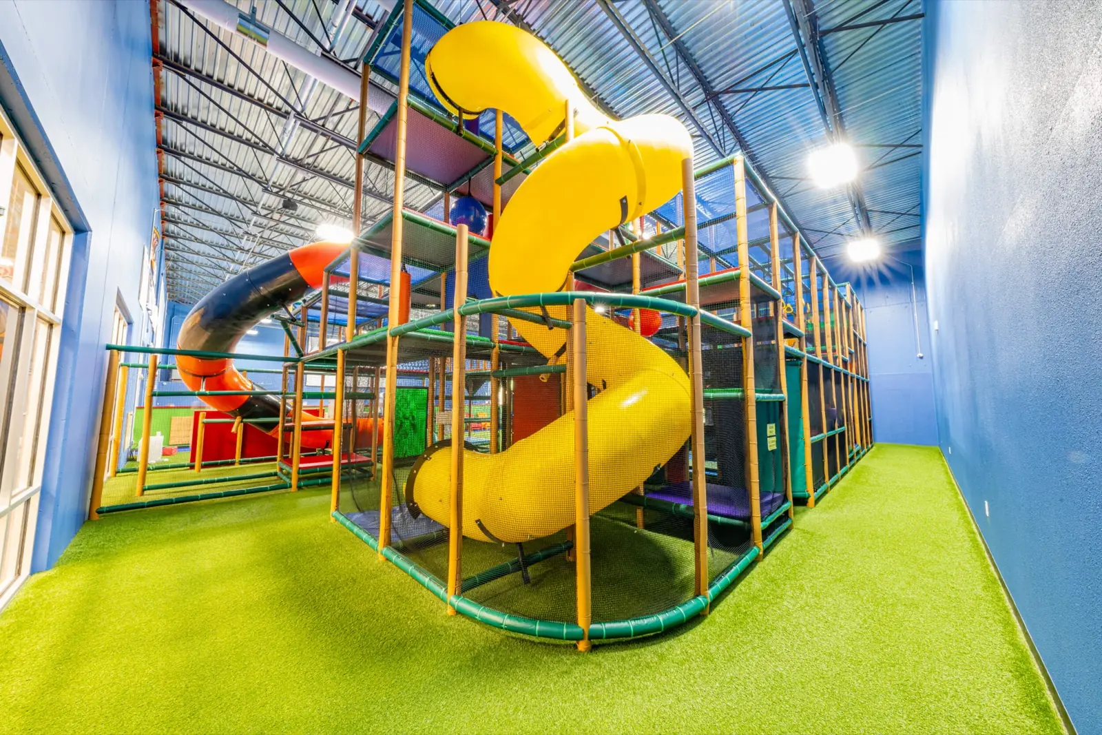 Yellow spiral slide and climbing structure inside Play Park MTX.